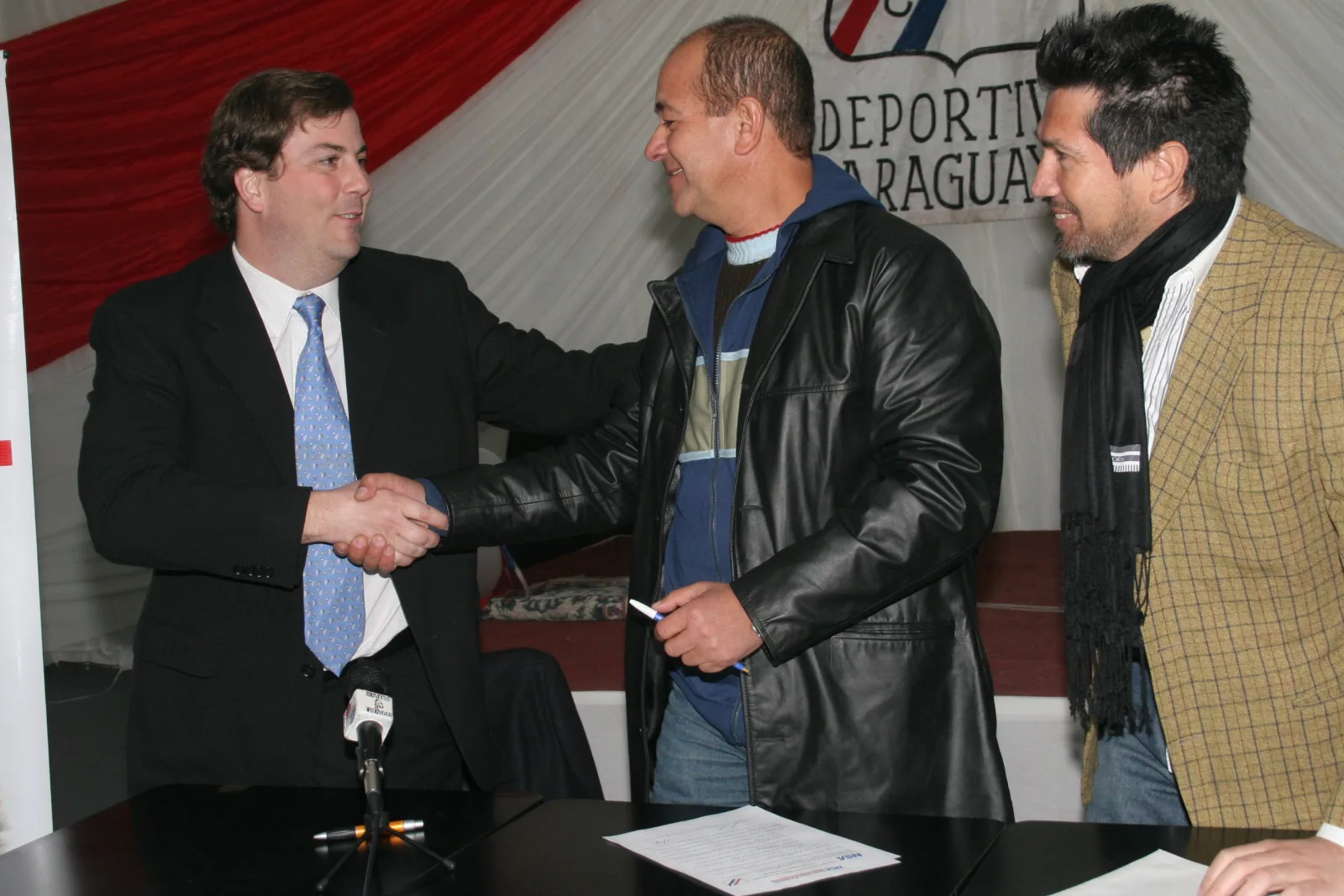 Per. Deportes 09 Camiseta Capos Robustiano Casares (I) Gerente de Marketing de NSA estrechando la mano a Ramón González, presidente del Deportivo Paraguayo y Lotti Guerrero (D)