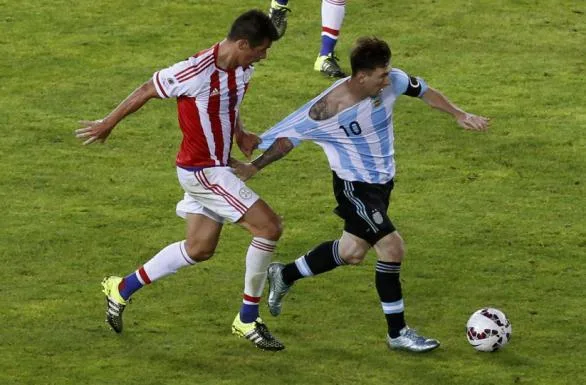 Argentina's Lionel Messi has his jersey pulled by Paraguay's Victor Caceres during their first round Copa America 2015 soccer match at Estadio La Portada de La Serena in La Serena, Chile, June 13, 2015. REUTERS/David Mercado