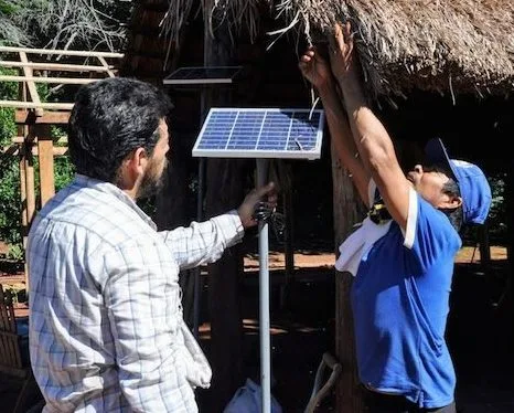 Especialistas instalan los paneles solares en una de las chozas de los beneficiados